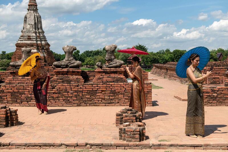 Visitors carrying parasols pose for photos at the 17th century Wat Chaiwatthanaram temple complex in the ancient Thai capital of Ayutthaya, north of Bangkok, as authorities reopened sites after a lockdown to halt the spread of the Covid-19.  AFP