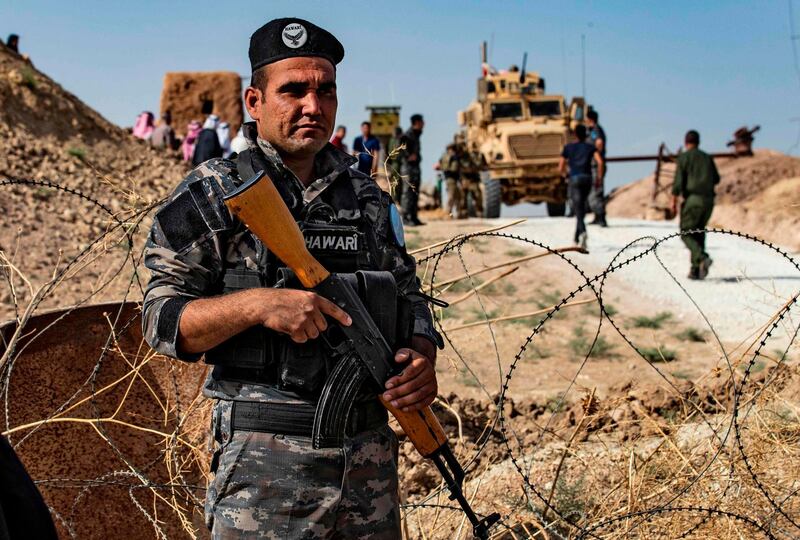 A member of Kurdish security forces stands guard during a demonstration by Syrian Kurds against Turkish threats next to a base for the US-led international coalition on the outskirts of Ras al-Ain town in Syria's Hasakeh province near the Turkish border. AFP