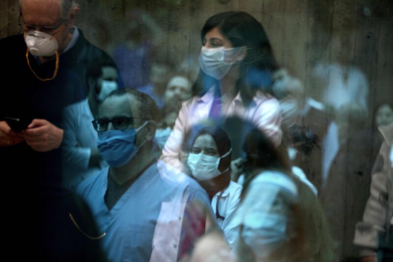 Medical staff at the Saint George Hospital University Medical Centre in charge of Covid-19 coronavirus patients reflections off a window as they listen to music played by a band thanking them for their efforts during the novel coronavirus pandemic. AFP