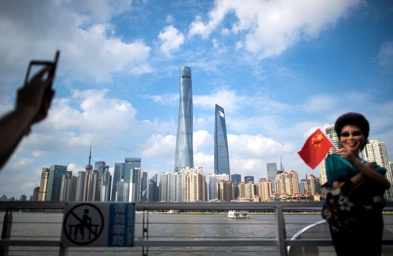 A woman poses for a picture with a Chinese flag in front of the skyline of the financial district in Shanghai on October 2, 2016.
China celebrated National Day on October 1 and annually marks the time with a week-long holiday break. / AFP PHOTO / JOHANNES EISELE