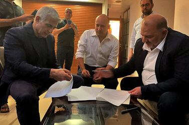 Mansour Abbas of Arab Israeli conservative party Raam signs a coalition agreement with opposition leader Yair Lapid and right-wing nationalist Naftali Bennett near Tel Aviv on June 2. AFP via United Arab List Raam