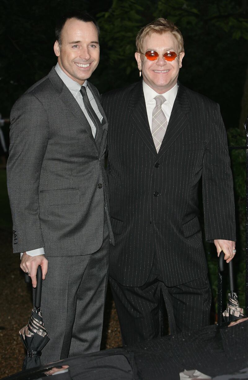 David Furnish and Elton John, in a pin-striped suit, arrive at Sir David Frost's summer party on July 5, 2007 in London. Getty Images