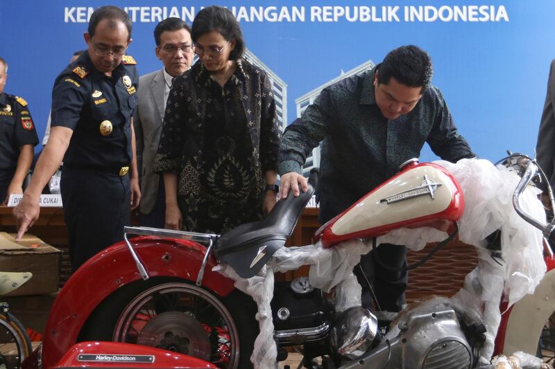 Indonesian Finance Minister Sri Mulyani Indrawati, second from right, and Minister of State-Owned Enterprises Eric Thohir, right, inspect a Harley Davidson motorcycle found by customs officials on a Garuda Indonesia's new Airbus A330-900 being delivered from France, prior to the start of a press conference in Jakarta, Indonesia, Thursday, Dec. 5, 2019. Thohir said he will fire and seek the prosecution of the head of the national airline after he was implicated in the smuggling the motorcycle into the country on the new jet. (AP Photo/Achmad Ibrahim)