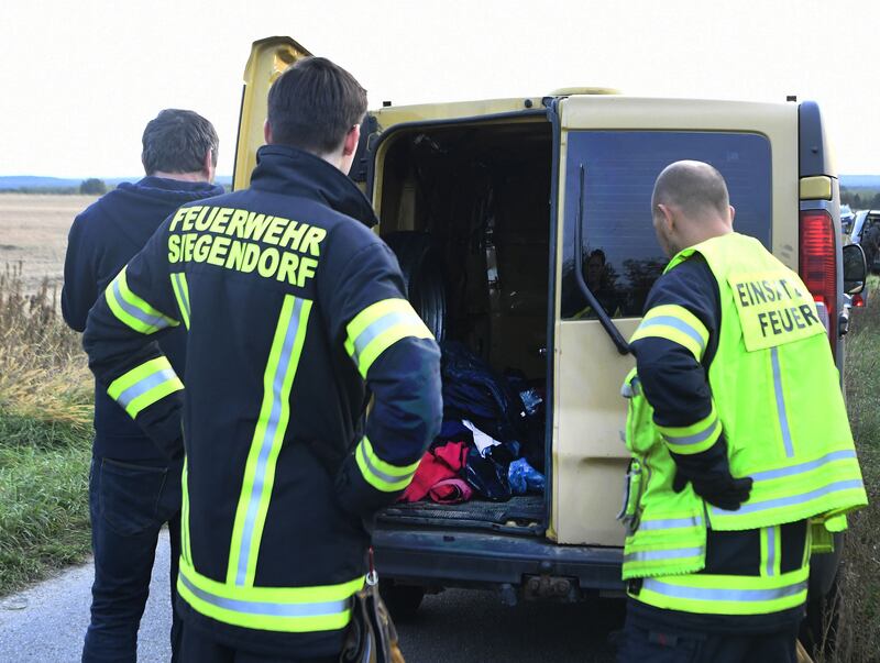 Austrian firemen inspect the van where two migrants were discovered dead. APA