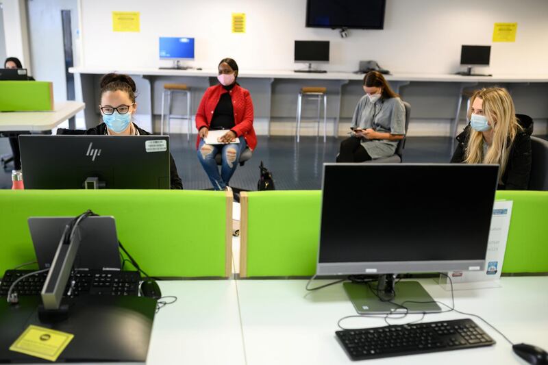 Students, wearing face masks to help mitigate the spread of the novel coronavirus COVID-19, work on computers in the Social Learning Zone at the University of Bolton, in Bolton, northern England on October 7, 2020. - The University of Bolton has introduced numerous Covid-safety measures across its campus including: airport-style temperature scanners, socially distanced seating, perspex screens and visors for lecturers, a bicycle loan scheme for students, one-way routes throughout campus buildings and additional online resources for student learning. Hundreds of thousands of students have begun a new academic year at universities across the UK. (Photo by OLI SCARFF / AFP)