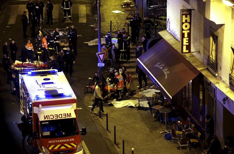 Rescue service personnel tend to the injured next to covered bodies outside a Paris restaurant attacked by gunmen on November 13, 2015. Philippe Wojazer / Reuters