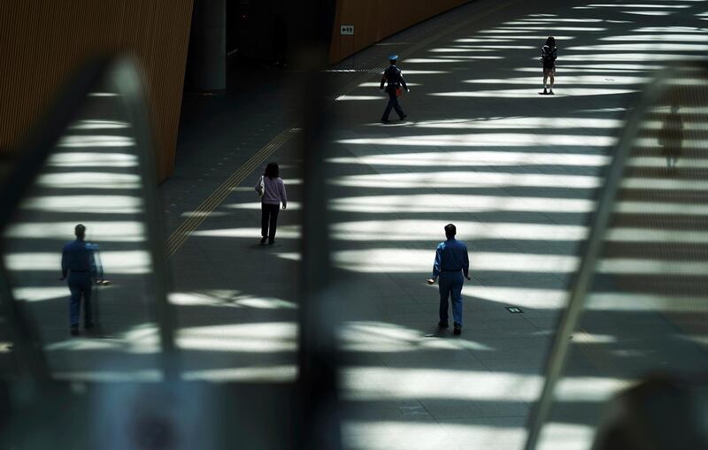 People walk in shade of a building in Tokyo. AP Photo