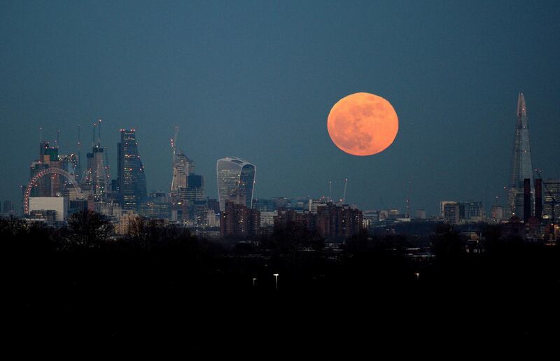 The moon rises over the London skyline, Wednesday Jan. 31, 2018. On Wednesday, much of the world will get to see not only a blue moon which is a supermoon, but also a lunar eclipse, all rolled into one celestial phenomenon. At left is the London Eye and at right The Shard. (KIrsty O'Connor/PA via AP)