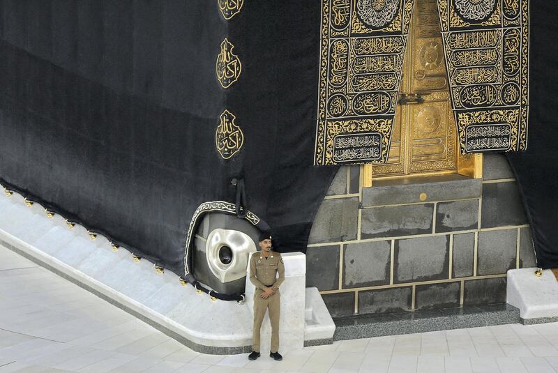 A Saudi security guard stands guard as worshippers perform Isha prayer (not in the picture) next to the Kaaba in Mecca's Grand Mosque, Islam's holiest site on April 27, 2020. - Saudi Authorities allowed for limit number of worshipers to enter the Grand mosque to perform prayers during the Islamic holy fasting month of Ramadan, amid unprecedented bans on family gatherings and mass prayers due to the coronavirus (COVID-19) pandemic. (Photo by STR / AFP)