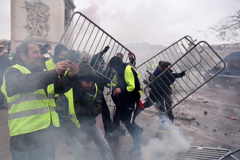 Demonstrators throws metal barriers during a protest of Yellow vests (Gilets jaunes) against rising oil prices and living costs, on the Champs Elysees avenue in Paris on December 1, 2018. 
 Thousands of anti-government protesters are expected today on the Champs-Elysees in Paris, a week after a violent demonstration on the famed avenue was marked by burning barricades and rampant vandalism that President Emmanuel Macron compared to "war scenes". / AFP / Lucas BARIOULET
