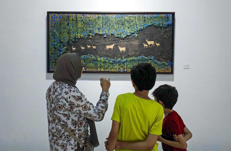 Libyans look at a painting by artist Elham el-Ferjani at the Hamim Gallery in the eastern city of Benghazi. The eastern Libyan city is hosting a rare week of culture featuring theatre, music, cinema and art, as the country attempts to turn the page on a decade of violence. AFP