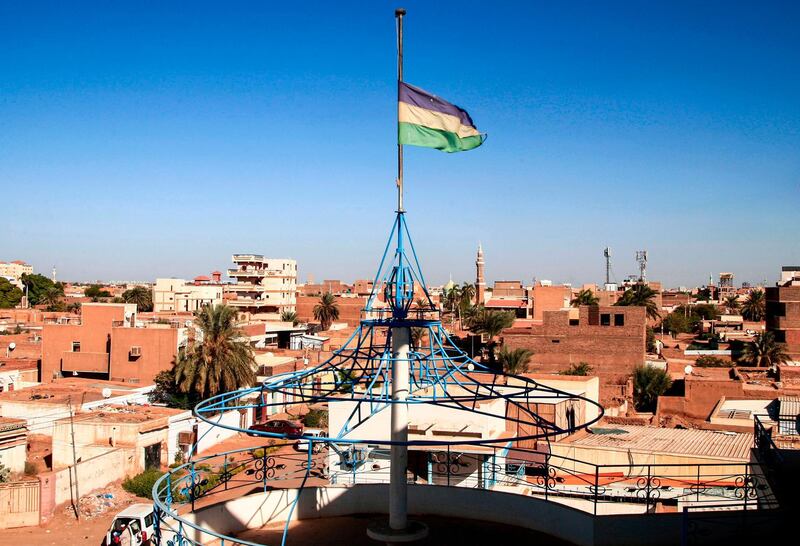 This picture taken on November 28, 2020 from the Sudanese capital's twin city of Omdurman shows a view of the blue-yellow-green tricolour flag used at the time of Sudan's independence flying at the house of Sayyid Ismail al-Azhari, who served as the first prime minister of independent Sudan from 1954 to 1956, and as President of Sudan from 1965 until his overthrow by a military coup in 1969. In Syria, Libya and more recently Sudan, Arab revolutionaries have begun brandishing old independence-era flags, attacking newer ones as symbols of the dictatorships they want to topple. Sudan's flag has three horizontal bands: blue for the Nile river, yellow for the desert and green for agriculture. Then president Gaafar al-Nimeiri dropped it in 1970, in favour of the colours of Arab nationalism. / AFP / Ebrahim HAMID
