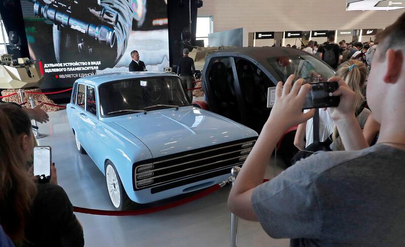 epa06969089 People take pictures of a blue prototype of CV-1 electric car manufactured by Concern Kalashnikov, Russian producer of a wide range of precision weapons, during ARMY 2018 International Military and Technical Forum in the Patriot Park in Alabino, Moscow region, Russia, 24 August 2018.  The car has driving range of 350 km between battery pack recharges and it accelerates from 0 to 100 km/h in 6 seconds. The presented retro-looking concept which is constructed on the basis of a Soviet-era hatchback IZh-21252 Kombi is used  as a stand for testing of developed complex systems.  EPA/SERGEI ILNITSKY