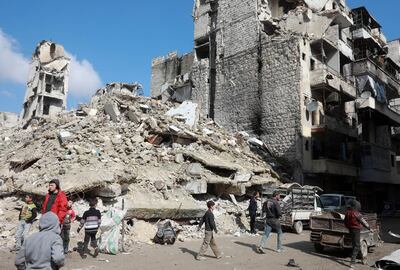 People walk past the rubble of buildings that were heavily damaged or destroyed during battles between rebel fighters and regime forces, in the former opposition-held district of Salaheddin in the northern Syrian city of Aleppo on February 11, 2019. (Photo by LOUAI BESHARA / AFP)