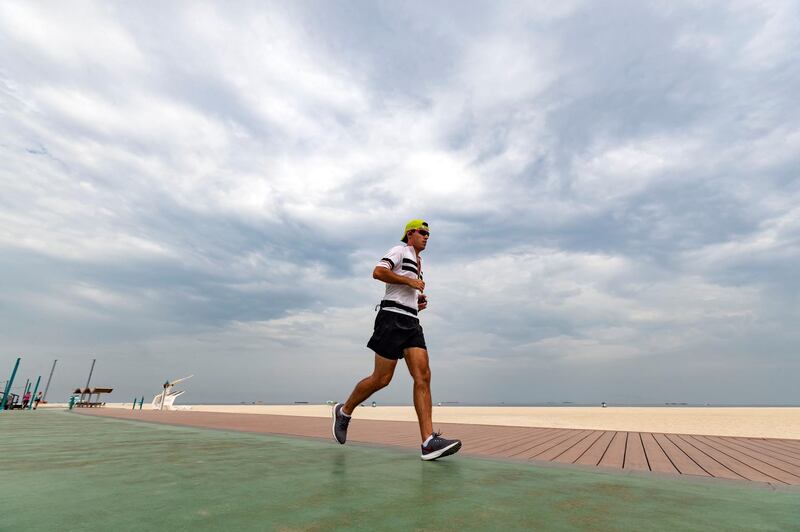 Dubai, United Arab Emirates - May 19, 2019: A runner exercises at Kite beach on a cloudy hazy day in Dubai. Sunday the 19th of May 2019. Jumeirah, Dubai. Chris Whiteoak / The National