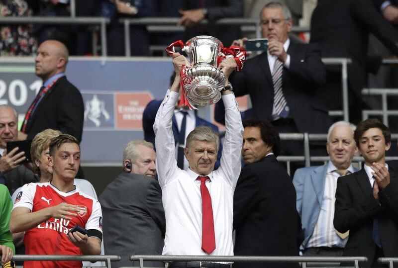 Arsene Wenger holding aloft the FA Cup trophy at the end of last season. Wenger led his side to silverware but they slipped out of the Premier League top four. Agencies