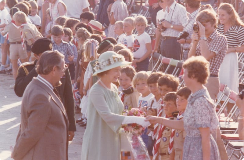 The queen greets a teacher at the school as pupils look on.