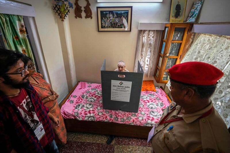 Rubi Paul, 89, sits on her bed and casts her vote at her residence using a postal ballot, in Guwahati, India. AP