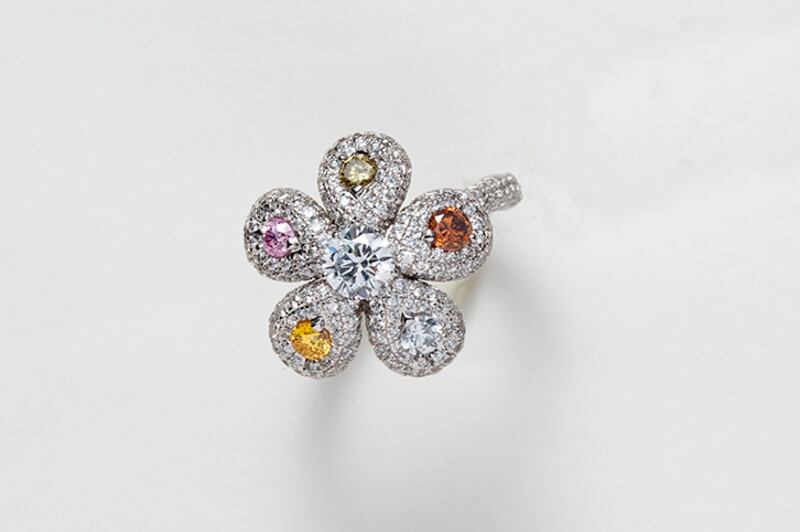 A ring shaped like a flower, in white and coloured diamonds