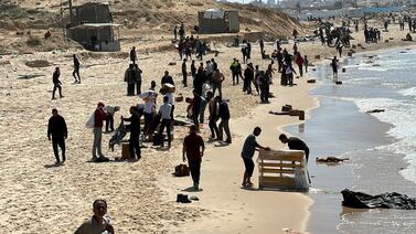 Palestinians on a beach collect aid dropped into the besieged enclave. Reuters