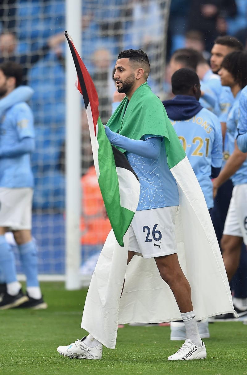 Riyad Mahrez wears the flag of Algeria while carrying the flag of Palestine on Sunday. Getty