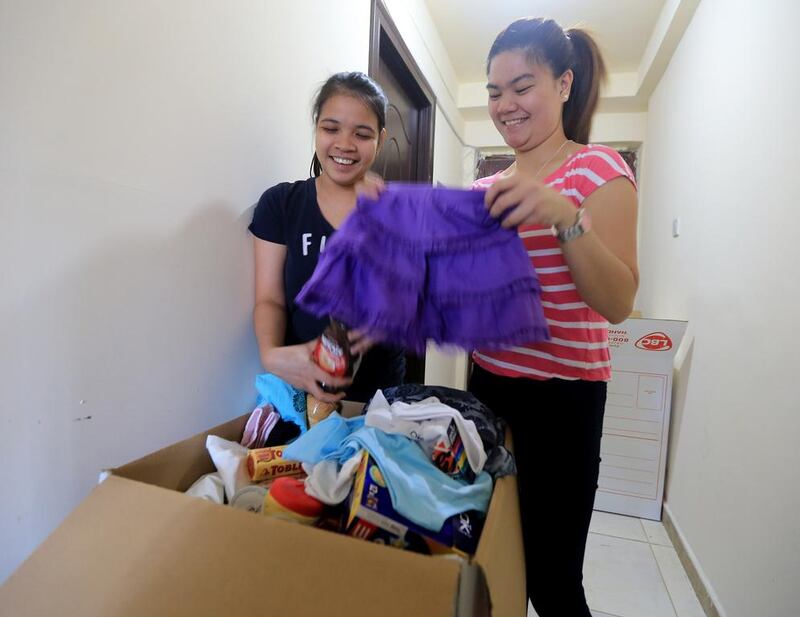 Sisters Lara, left, and Leah Ventura pack a balikbayan box to be sent home to the Philippines. Ravindranath K / The National