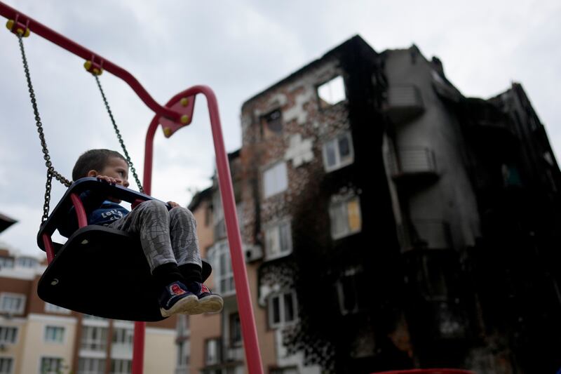 A boy, Yarik, plays in a playground in front a building destroyed during attacks, in Irpin. AP