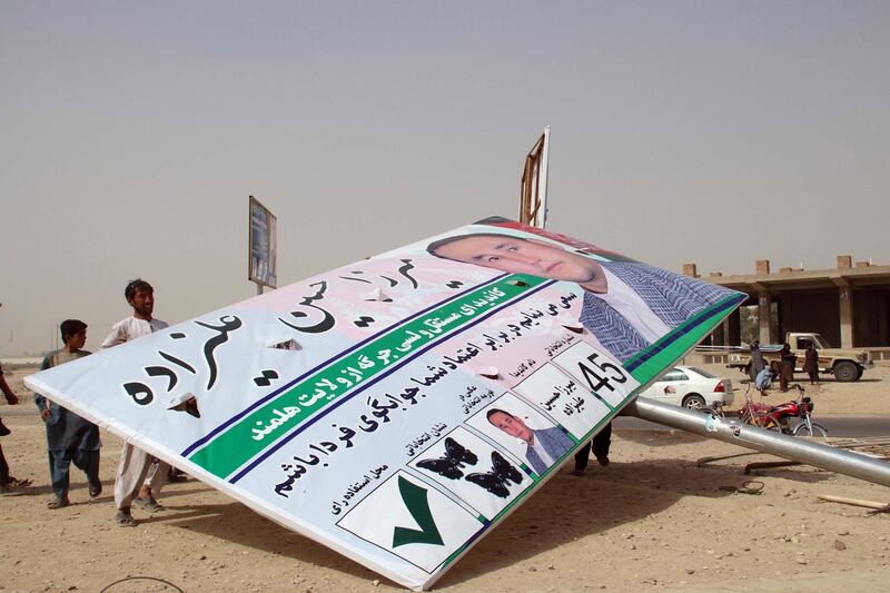 epa07079213 Afghans stand beside an electoral campaign poster that was uninstalled by unknown men, as security has been intensified following the announcement by Taliban militants to boycott the upcoming Parliamentary elections, in Helmand, Afghanistan, 08 October 2018. The Taliban on 08 October appealed to the people of Afghanistan to boycott the upcoming parliamentary elections in the country, calling them an attempt to legitimize the presence of foreign troops in the country. The campaign for the elections, set for Oct. 20, began around 10 days ago and will continue for around three weeks.  EPA/WATAN YAR