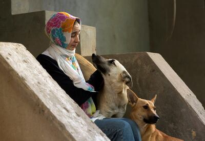 Manar Saeeda, 25, with stray dogs at the entrance to her home in Cairo in 2021. Reuters