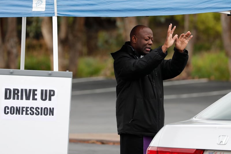 Rev. Luke Ssemakula (L) gives a blessing after hearing a parishioner's confession in the parking lot of St. Augustine Catholic Church during the ongoing coronavirus pandemic, in Pleasanton, California, USA.  EPA