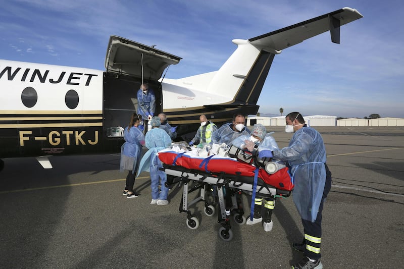 Paramedics, nurses and doctors use a trolley to transfer a coronavirus patient from an ambulance into a medical aircraft in Bastia on the French Mediterranean island of Corsica. AFP