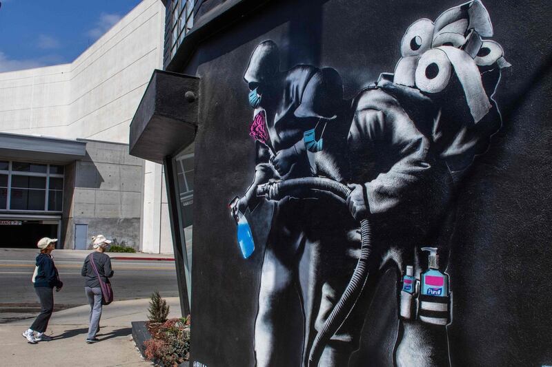 People walk by an apocalyptic mural by Hijackhart, where soldiers wearing face masks fight Covid-19 with disinfectant and hand sanitizers during the coronavirus pandemic in Los Angeles, California. AFP