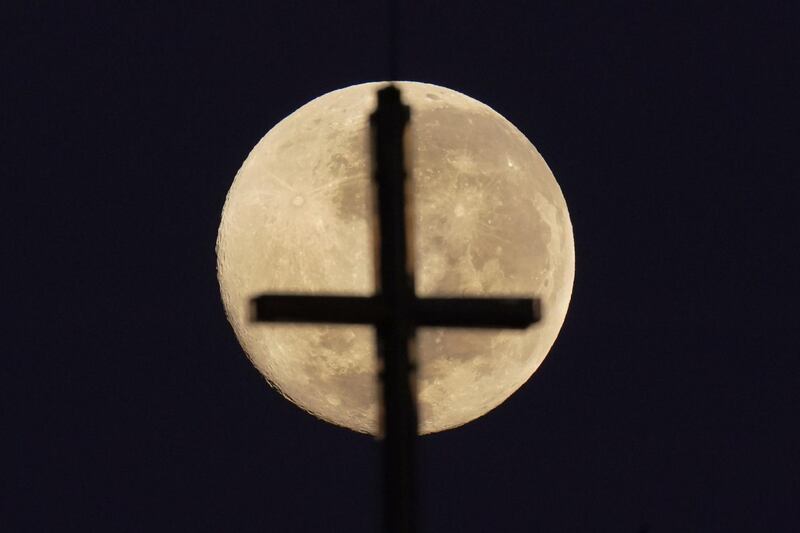 A church cross is silhouetted by the pink supermoon, in Melbourne, Australia. EPA