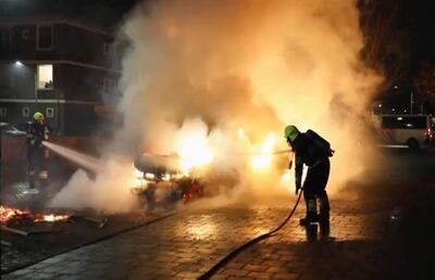 In this grab taken from video on Monday, Jan, 25, 2021, firefighters extinguish a vehicle set on fire by rioters, in Haarlem, Netherlands. Groups of youths have confronted police in several Dutch cities defying the countryâ€™s coronavirus curfew and throwing fireworks. Police in the port city of Rotterdam used a water cannon and tear gas in an attempt to disperse a crowd of rioters Monday night. (Mizzle Media via AP)