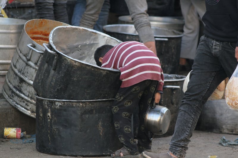 A Palestinian child searches for food scraps at a street kitchen in Deir Al Balah, central Gaza, on March 19. Bloomberg