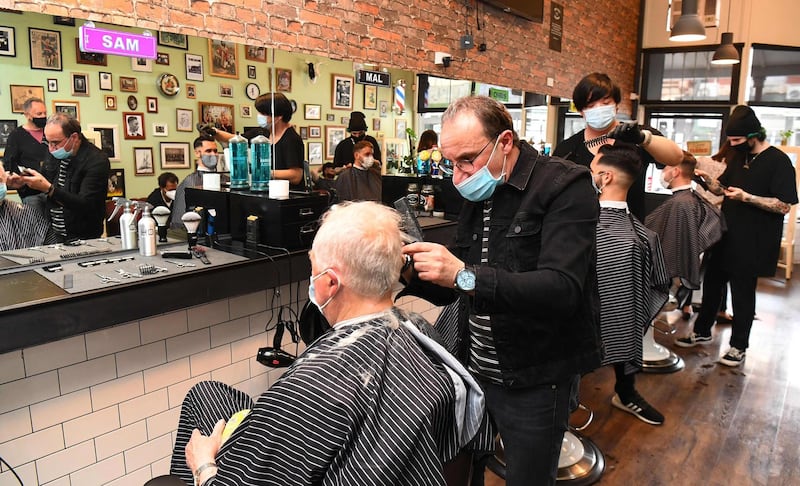 Men have their haircut at a barber shop in Melbourne, as some of the city's three-month-old stay-at-home restrictions due to the Covid-19 outbreak were further eased on falling infection rates. AFP