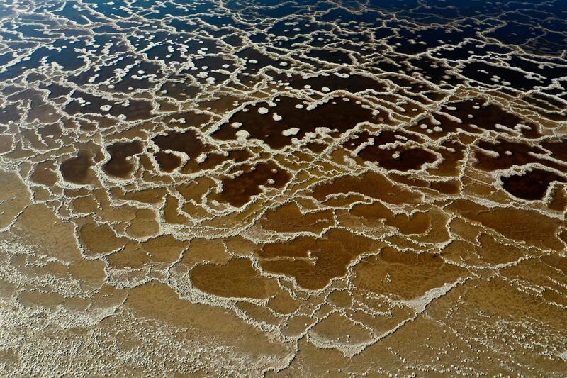 Patterns formed by crystalised minerals on the surface of evaporation ponds in the Dead Sea, near the southern Israeli moshav of  Ein Tamar. The water recedes about a metre every year, leaving behind a lunar-like landscape whitened by salt and perforated with gaping holes.