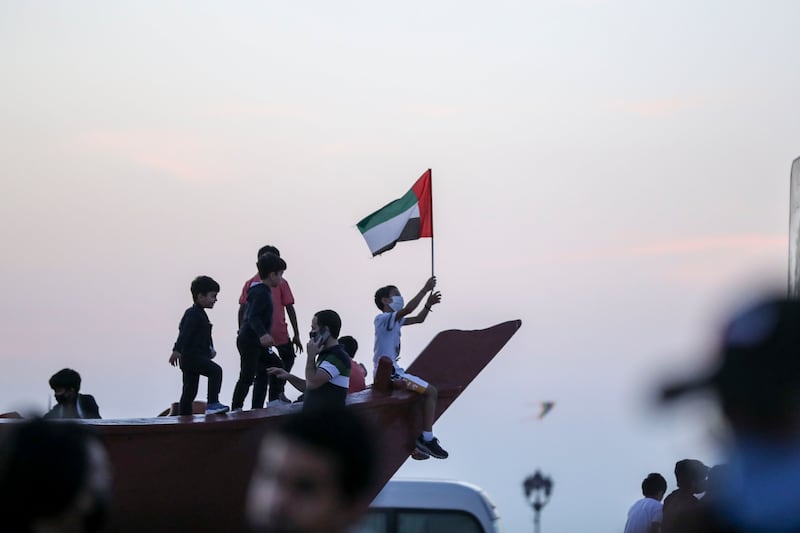 A young boy waves the UAE flag from the dhow monument at the Corniche as part of the 50th National Day celebrations in Abu Dhabi. Khushnum Bhandari / The National