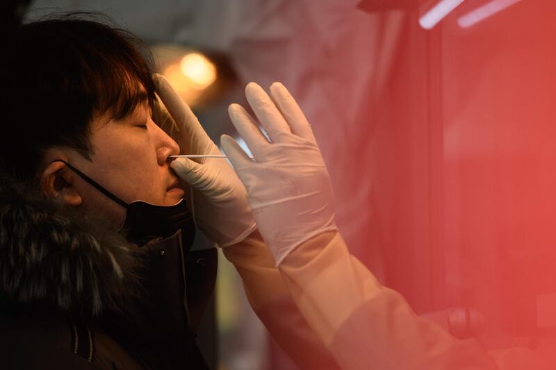 TOPSHOT - Office workers and city government employees receive a covid-19 novel coronavirus test at a temporary testing centre outside city hall in Seoul on December 17, 2020. / AFP / Ed JONES
