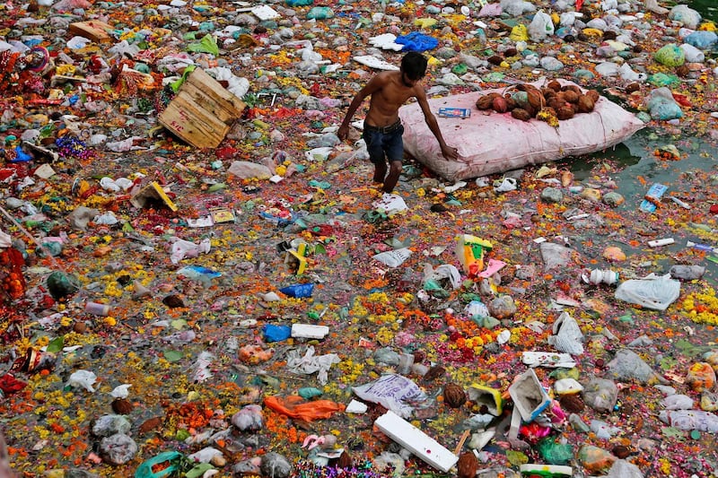 An Indian man searches for reusable items amid offerings and worship materials on the bank of river Sabarmati after the end of Dashama festival in Ahmadabad, India. AP Photo