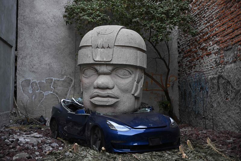 Artwork by artist Chavis Marmol of a Tesla 3 car crushed by a nine-tonne Olmec-inspired head, in Mexico City. AFP