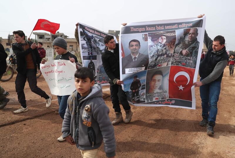 Syrians hold portraits of Turkish soldiers killed in Syria and Turkey's flag as they demonstrate near a Turkish military post in the Syrian town of Binnish on the Syria-Turkey border. AFP