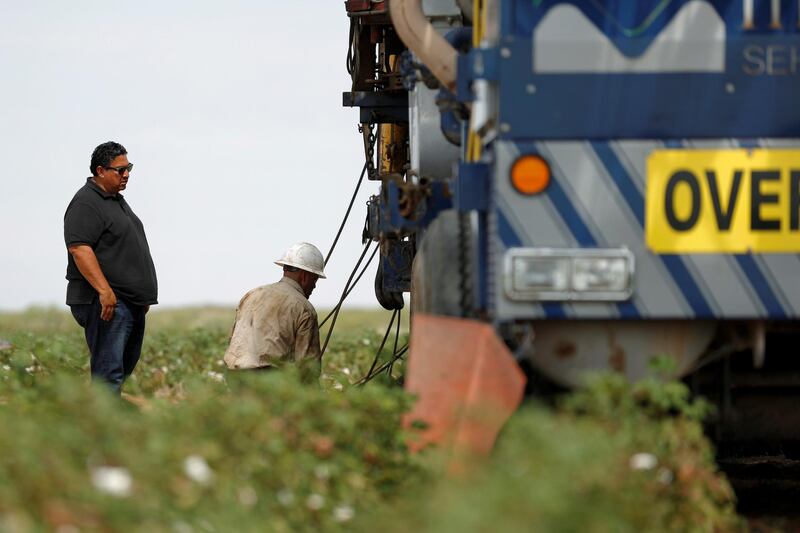 Johnny Vega (left), the president and CEO of Mico Services, looks on as an oil field worker operates a swabbing rig in Seminole, TX, U.S. September 19, 2019. Picture taken September 19, 2019.    REUTERS/Adria Malcolm