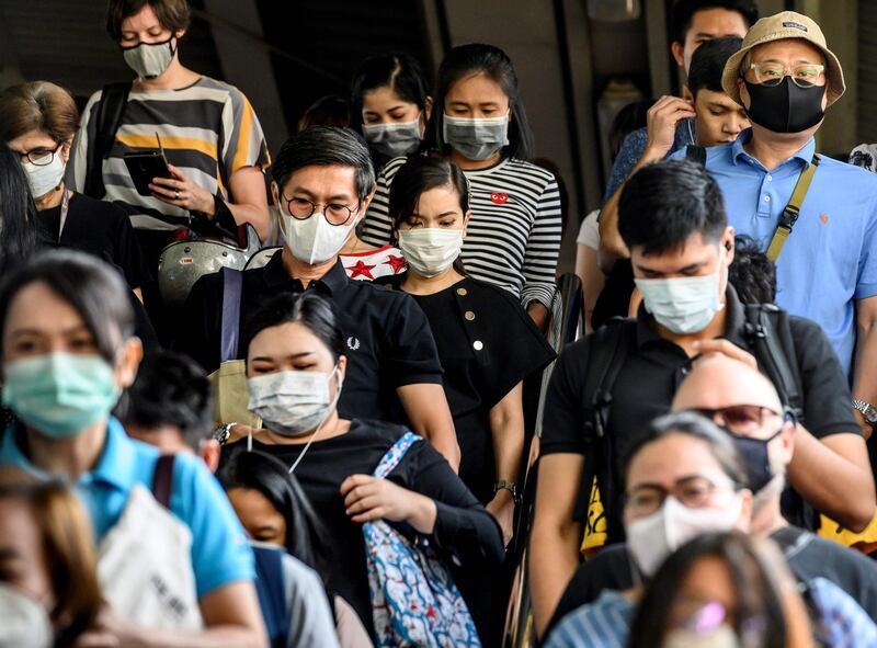 People wearing protective facemasks leave the city commuter train station in Bangkok. AFP