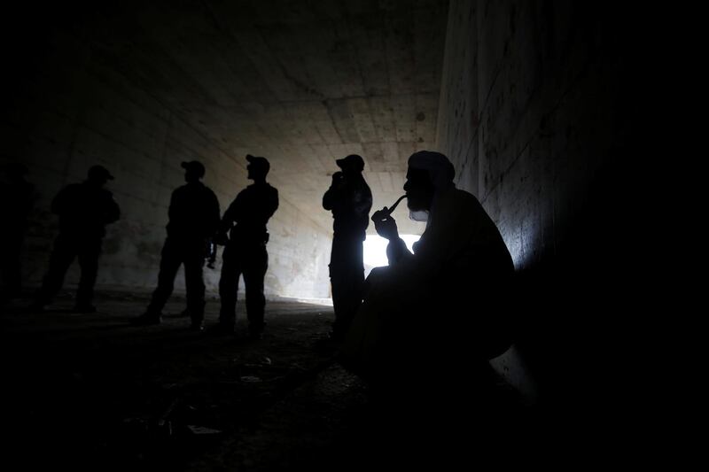 A Palestinian smokes a pipe as Israeli forces stand guard in the Bedouin village of Khan al-Ahmar, a built-up area slotted for demolition in the occupied West Bank. Reuters