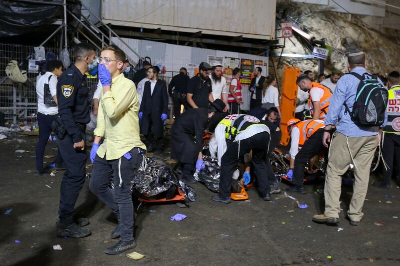 Israeli security officials and rescuers carry away victims who died during Lag BaOmer celebrations at Mount Meron in northern Israel. JINIPIX via AP