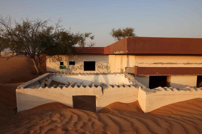 A house lies half buried in the desert sand, in the abandoned village of Al Madam. Some houses are now completely enclosed within dunes. AFP