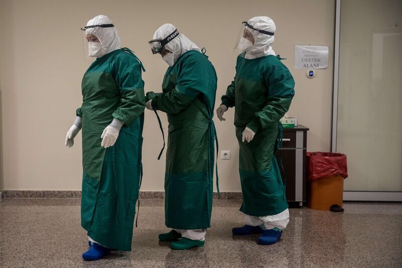 Medical staff get dressed in personal protective equipment before cleaning and disinfecting a bed after a Covid-19 patient was discharged from the Kartal Dr Lutii Kirdar Education and Research Hospital’s Intensive Care Unit on May 08, 2020 in Istanbul. Getty Images/AFP