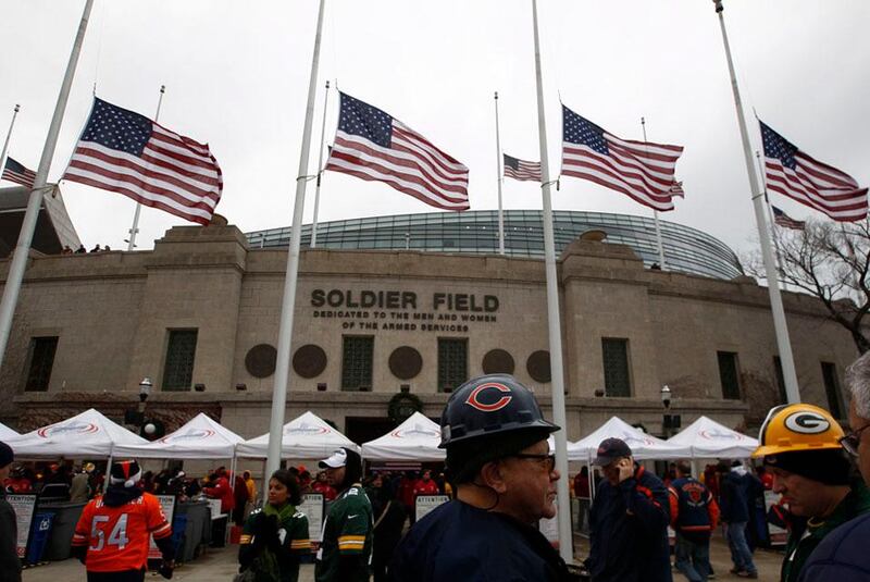 U.S. flags fly at half staff in memory of 20 children and six adults who lost their lives  in a mass shooting at Sandy Hook Elementary School, as football fans arrive for an NFL football game at Soldier Field in Chicago, December 16, 2012. REUTERS/Jim Young (UNITED STATES - Tags: SPORT FOOTBALL)