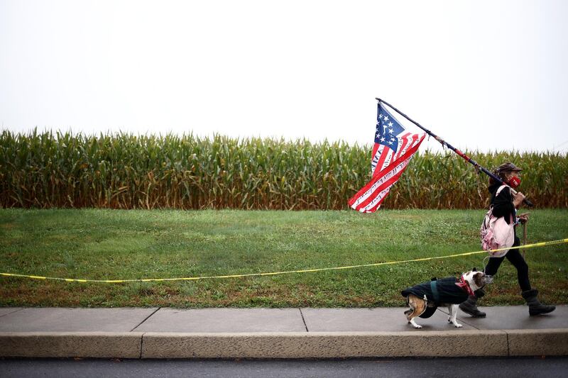 A Trump supporter holds a flag as she arrives with her dog to a rally in Lancaster, Pennsylvania in October. Reuters
